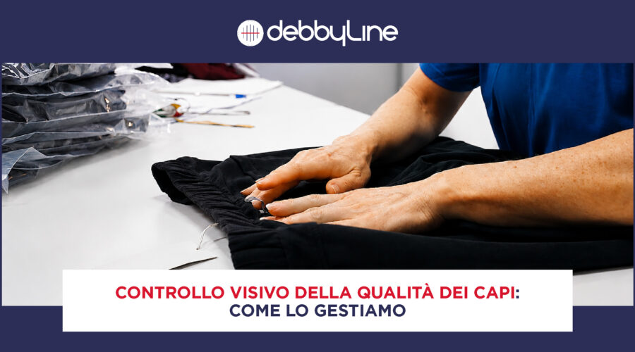 Operatrice DebbyLine esegue il controllo visivo della qualità dei capi su un paio di pantaloni: si vedono le sue mani sul capo, sopra un tavolo bianco